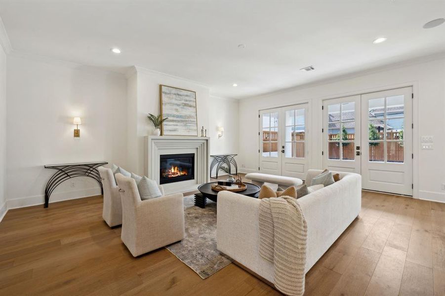 Family room with engineered white oak hardwood floors, built-in speakers, and Mahogany French doors leading to covered patio and backyard.