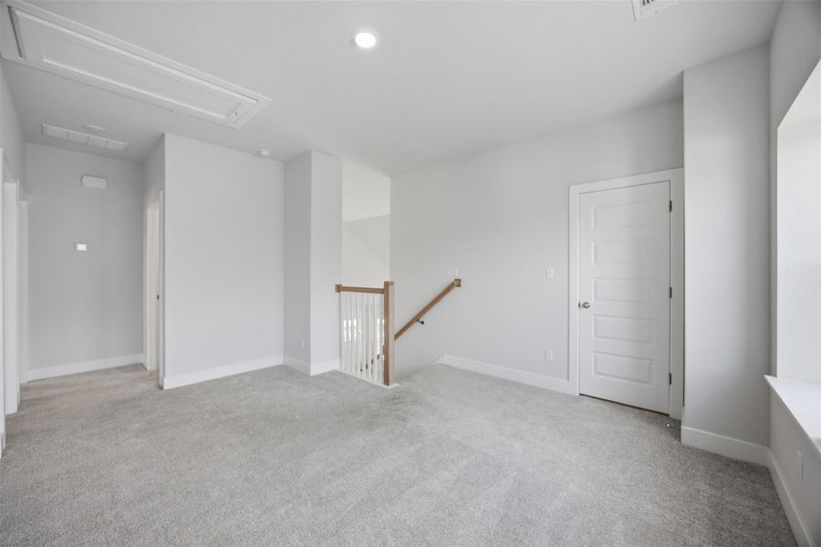 A spacious secondary living area features soft carpeting and natural wood handrails.