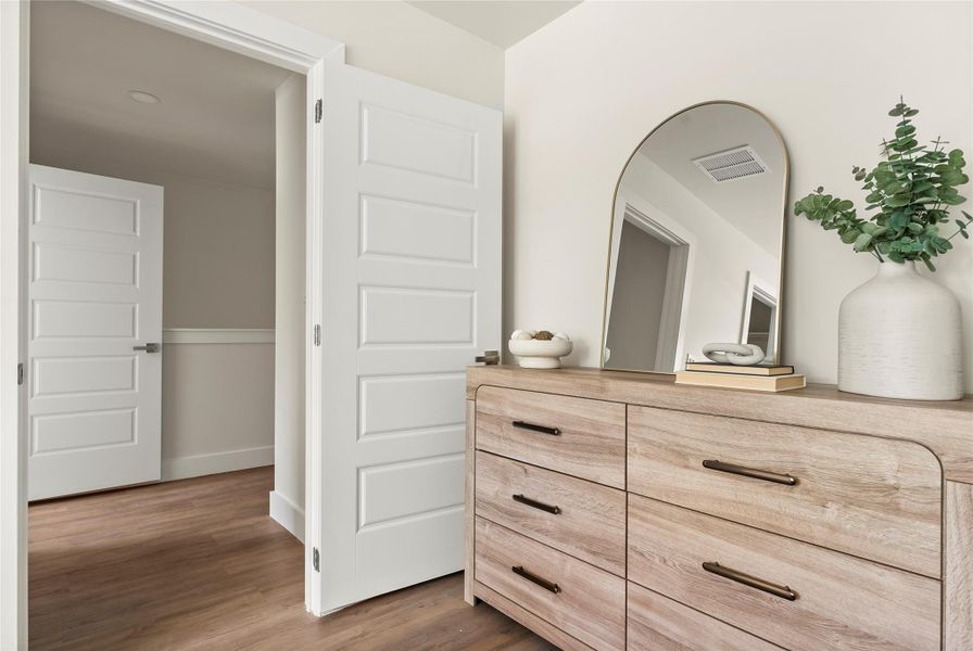 Blonde wood dresser and arched mirror complement this bedroom's neutral tones and durable flooring.