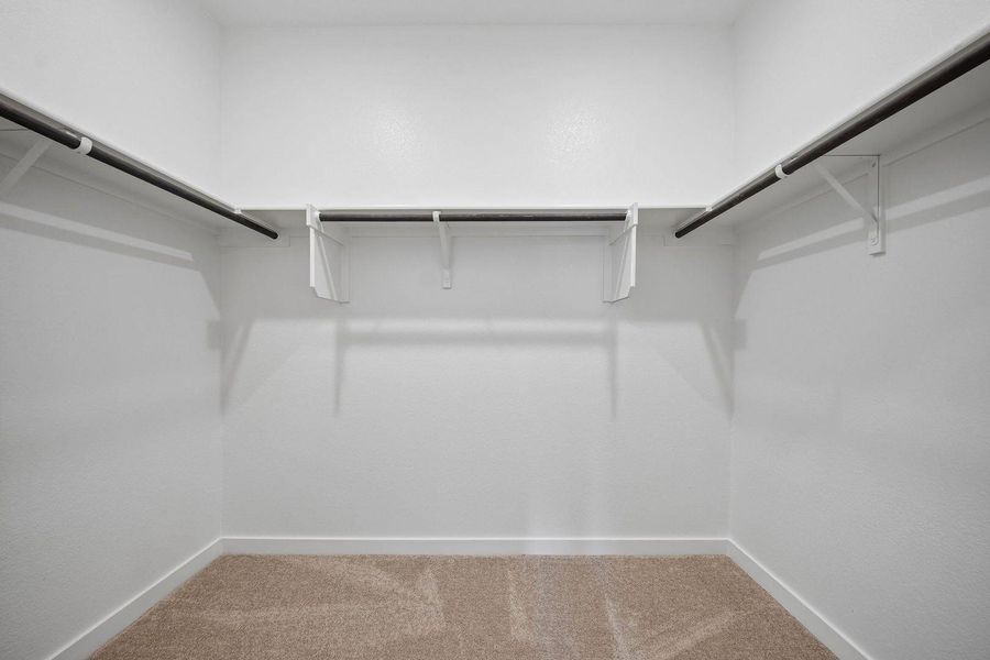 A spacious walk-in closet with ample hanging space and neutral carpeting awaits your wardrobe. A spacious walk-in closet with ample hanging space and neutral carpeting awaits your wardrobe.