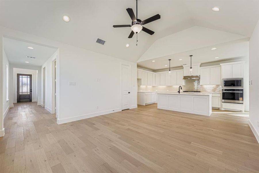 Unfurnished living room featuring recessed lighting, light wood finished floors, a ceiling fan, and lofted ceiling Unfurnished living room featuring recessed lighting, light wood finished floors, a ceiling fan, and lofted ceiling