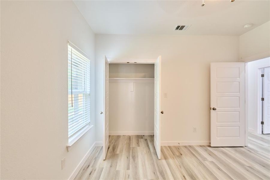 Bedroom featuring light wood-finish flooring, white walls, and a window with blinds