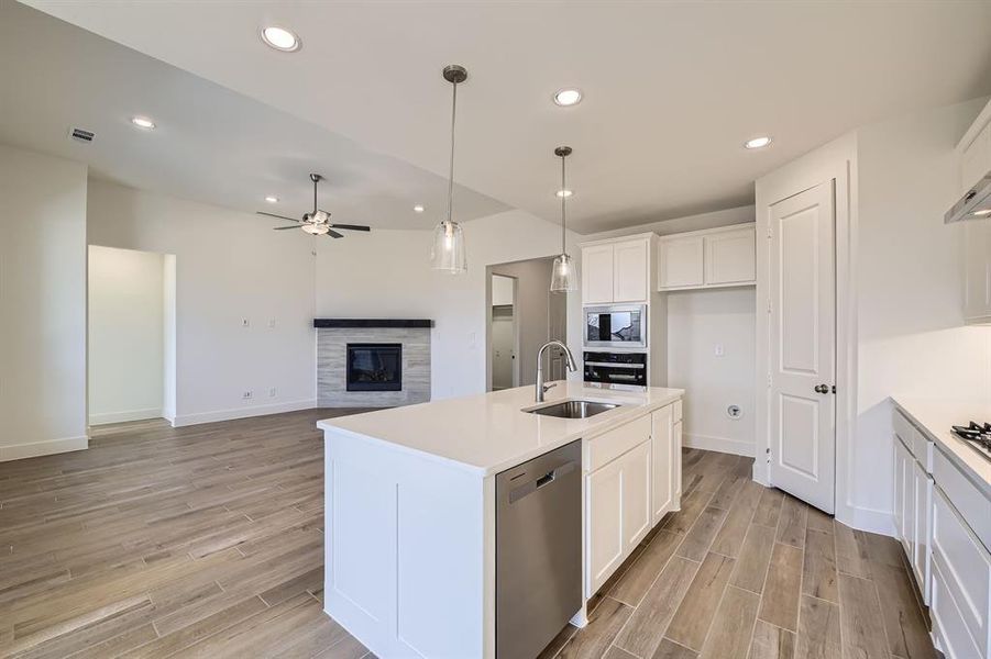 Kitchen with a glass covered fireplace, white cabinetry, appliances with stainless steel finishes, and wood tiled floor