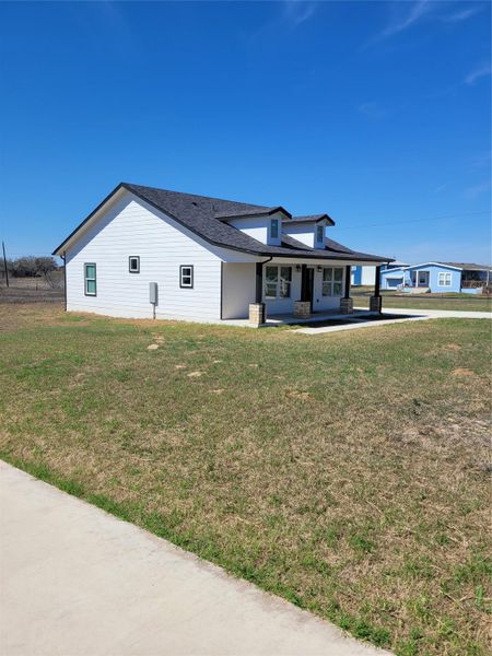 View of front of home featuring covered porch, a front yard, and roof with shingles