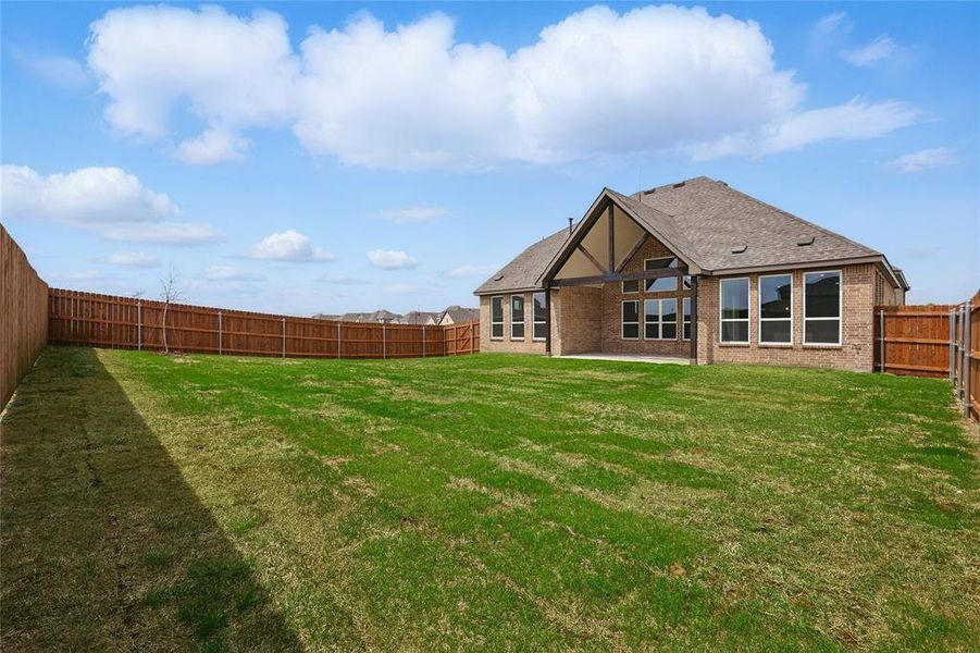 Back of house featuring a lawn, a shingled roof, a fenced backyard, and a patio