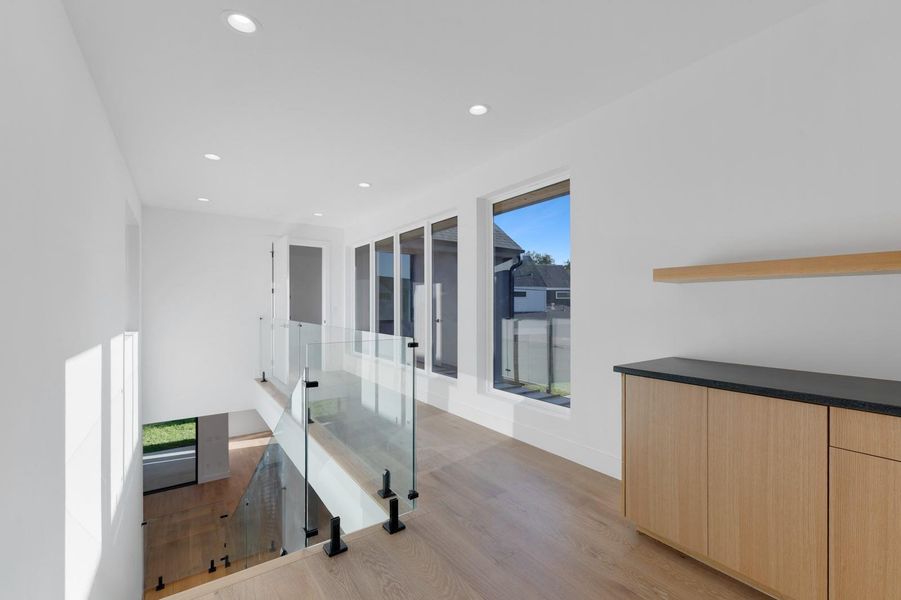 Hall with light wood finished floors and recessed lighting