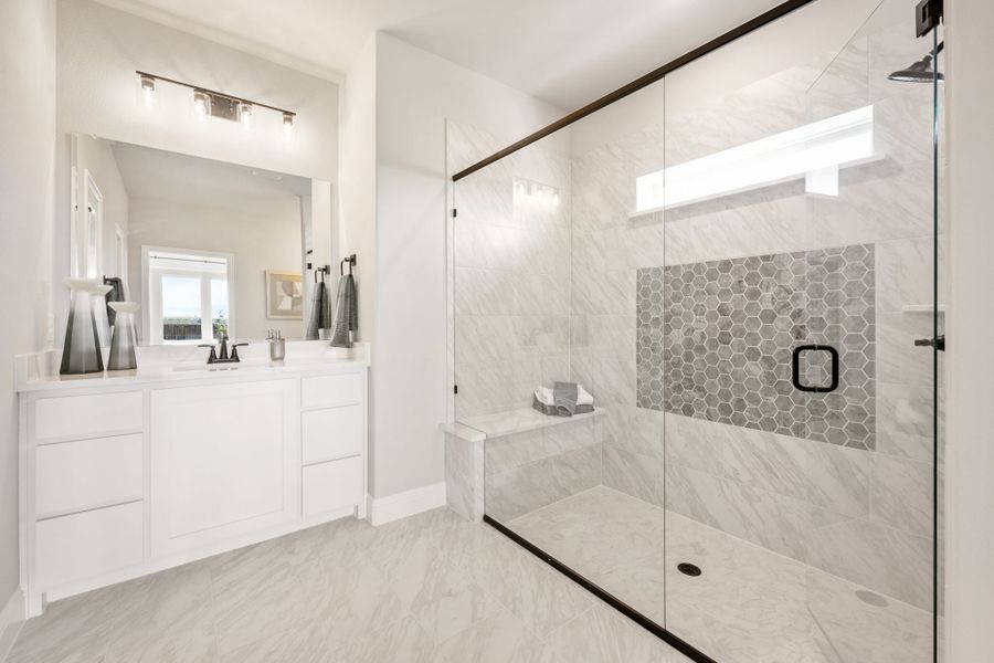 Bathroom with white vanity, large glass walk-in shower, marble tile walls, and hexagon tile accent
