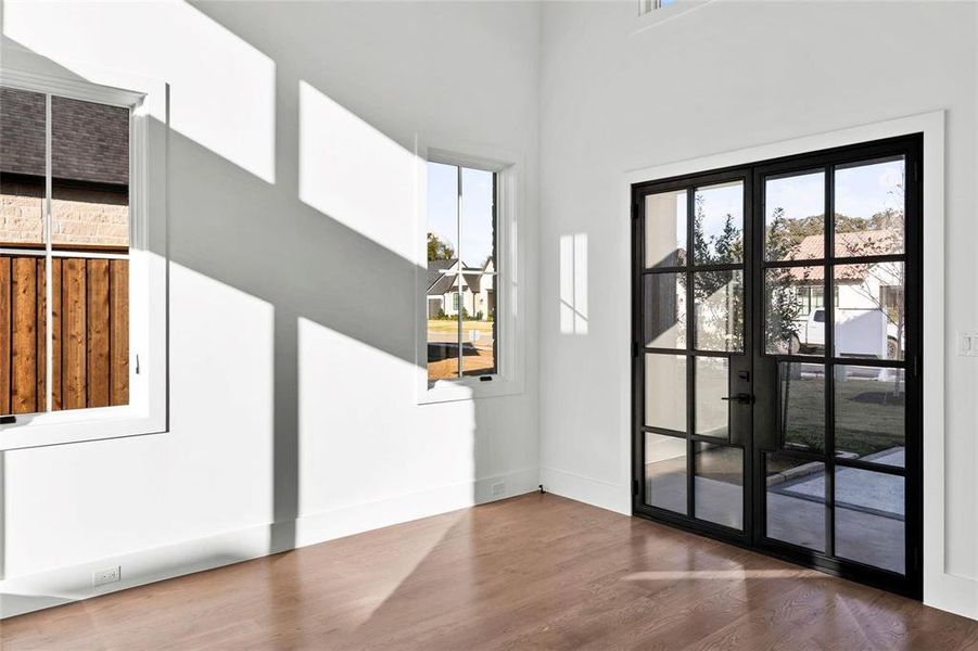 Doorway featuring plenty of natural light, wood finished floors, a high ceiling, and french doors Doorway featuring plenty of natural light, wood finished floors, a high ceiling, and french doors