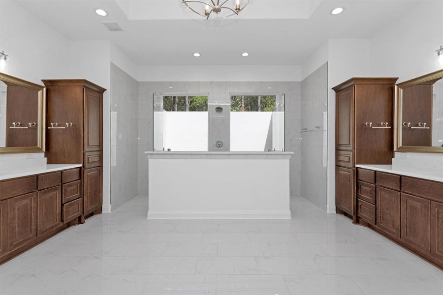 This luxurious spa-inspired bath features dual vanities, rich wood cabinetry, and an oversized walk-in shower framed by picture windows that bring the outdoors in with total privacy. This luxurious spa-inspired bath features dual vanities, rich wood cabinetry, and an oversized walk-in shower framed by picture windows that bring the outdoors in with total privacy.