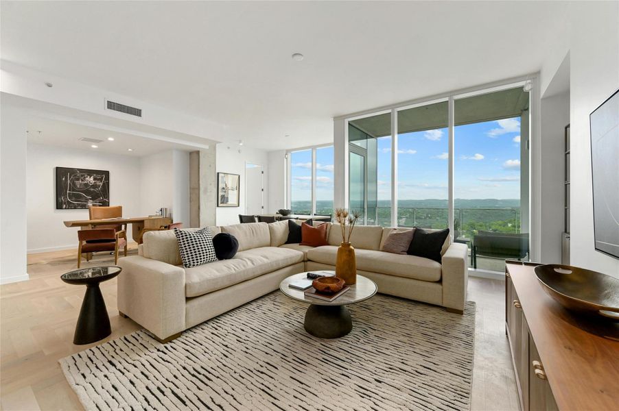 Modern elegance meets breathtaking views in this light-filled living space. Floor-to-ceiling windows frame a spectacular sunset skyline, while the open-concept design seamlessly connects the living, dining, and den areas. Neutral tones, sleek finishes, and contemporary furnishings create a sophisticated yet inviting ambiance in this newly constructed luxury residence.