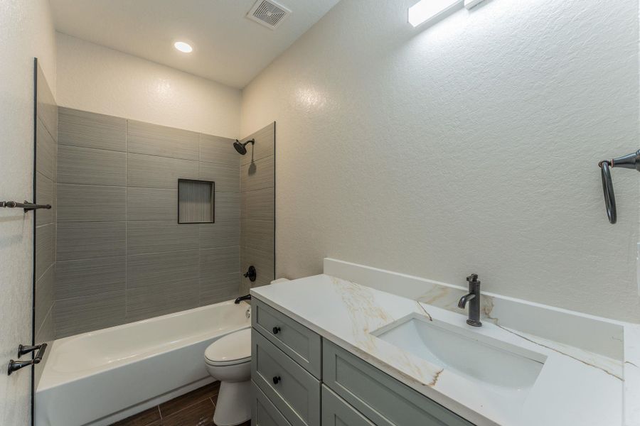 Contemporary bathroom featuring a tub-shower combination with gray subway tile surround and integrated niche