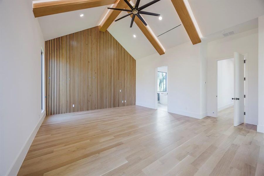 Unfurnished living room featuring beamed ceiling, light wood-style flooring, ceiling fan, high vaulted ceiling, and wood walls Unfurnished living room featuring beamed ceiling, light wood-style flooring, ceiling fan, high vaulted ceiling, and wood walls