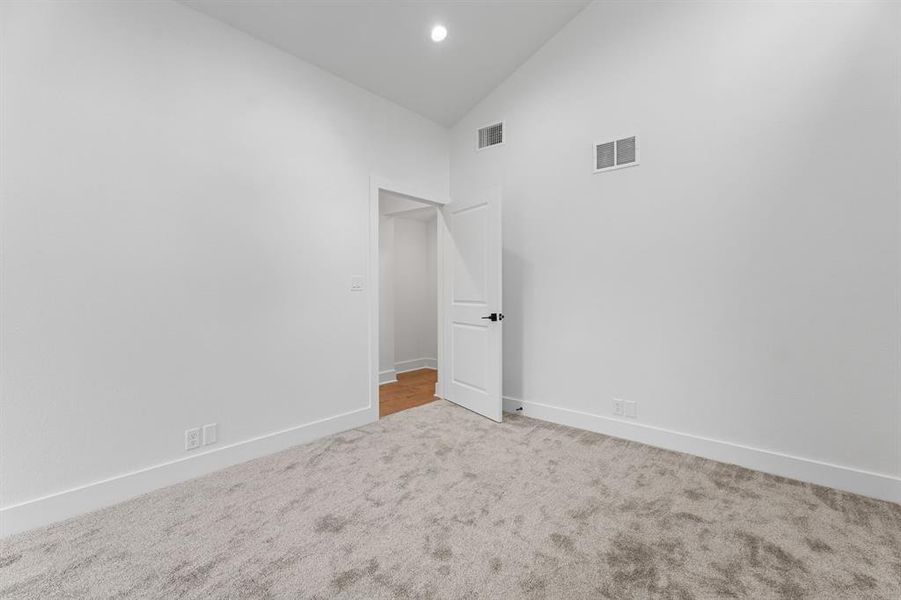 Unfurnished room with high vaulted ceiling and carpet flooring Unfurnished room with high vaulted ceiling and carpet flooring