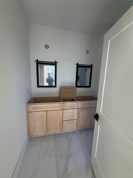 Full bath with light marble finish floors, double vanity, and a bath