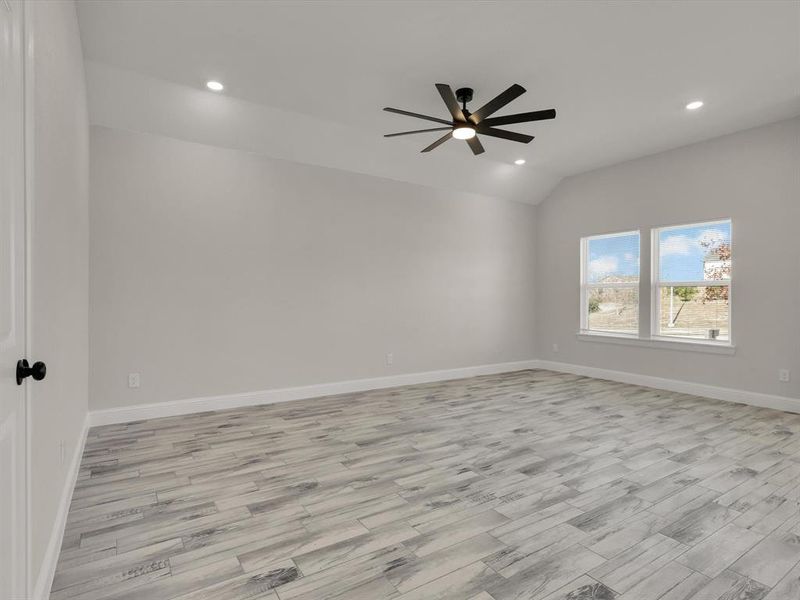 Spare room featuring ceiling fan, light hardwood / wood-style floors, and vaulted ceiling