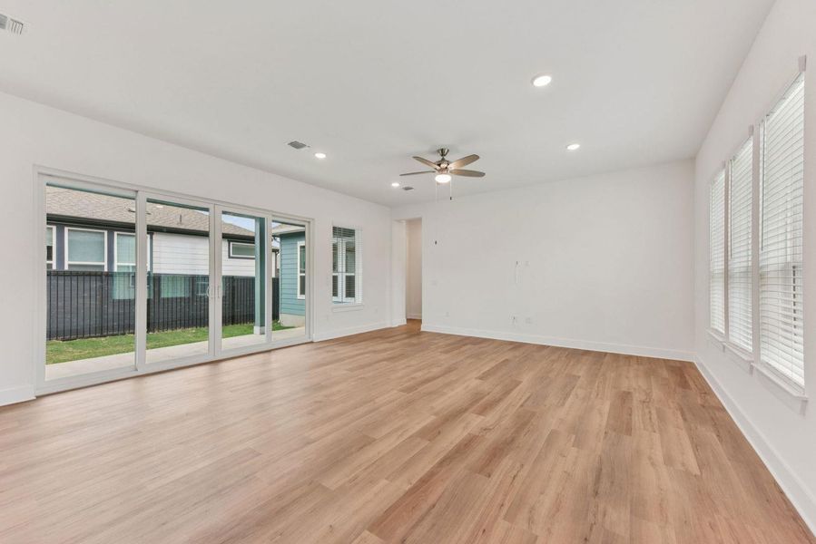 Spacious room featuring wood-finish flooring, white walls, and recessed lighting