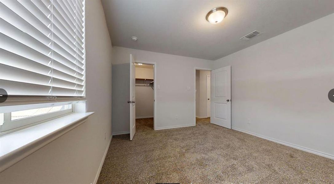 Unfurnished bedroom featuring baseboards, carpet, a spacious closet, and a closet