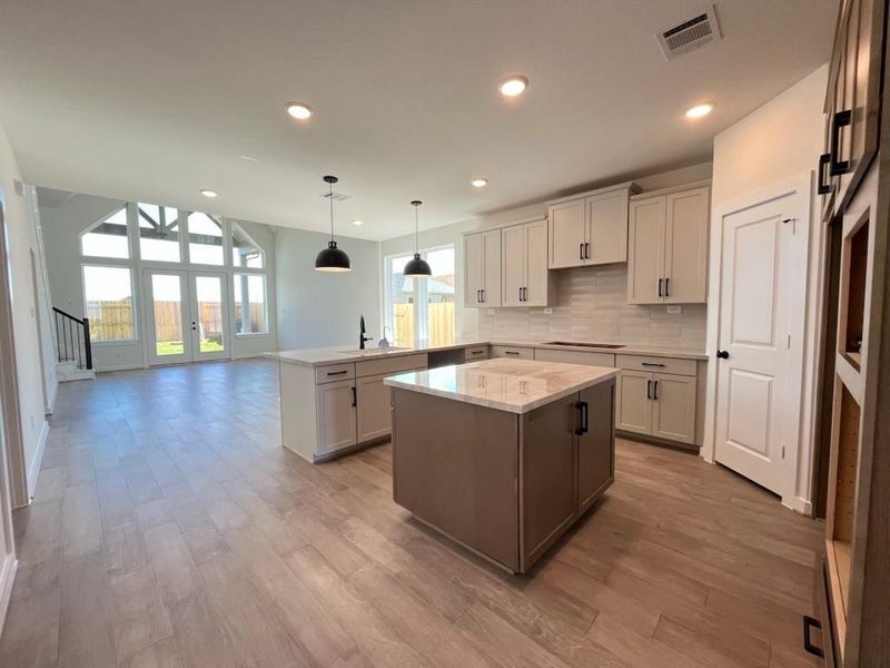 The open kitchen features a sleek 5-burner cooktop, perfect for cooking and entertaining. A spacious walk-in pantry adds plenty of storage and convenience.