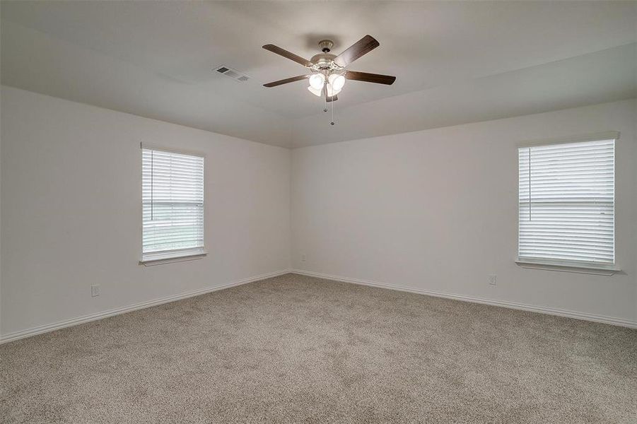 Unfurnished room with light colored carpet, healthy amount of natural light, and ceiling fan