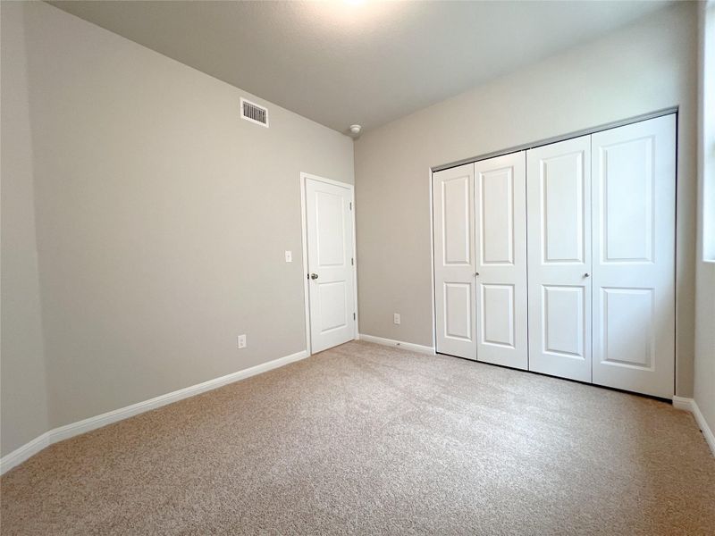 A comfortable bedroom featuring soft carpeting and a spacious bi-fold closet, offering ample storage. A comfortable bedroom featuring soft carpeting and a spacious bi-fold closet, offering ample storage.