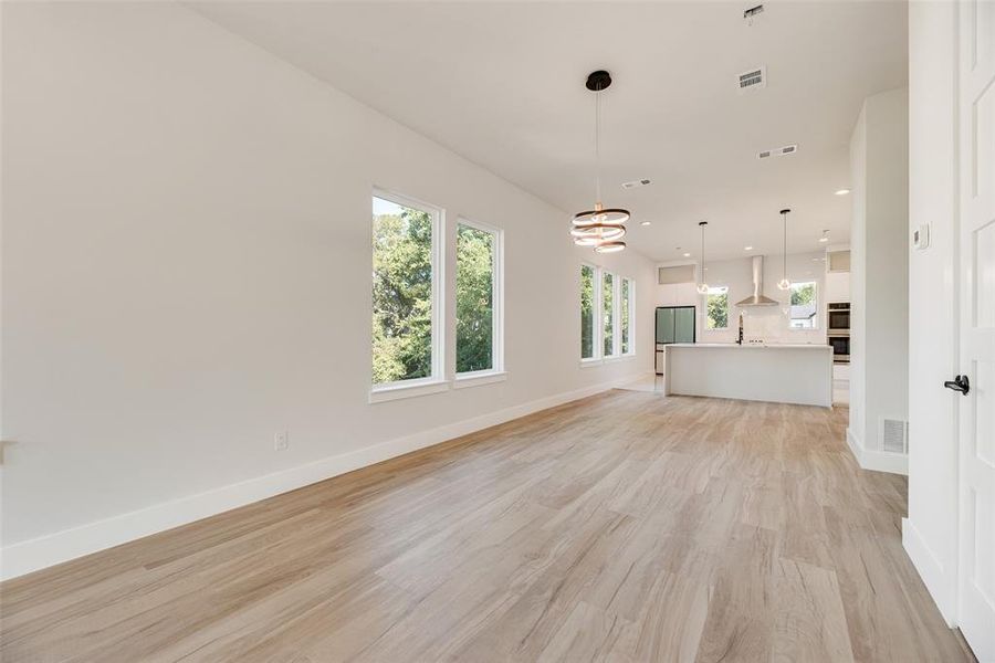 Unfurnished living room featuring light wood-style flooring, a chandelier, and recessed lighting Unfurnished living room featuring light wood-style flooring, a chandelier, and recessed lighting