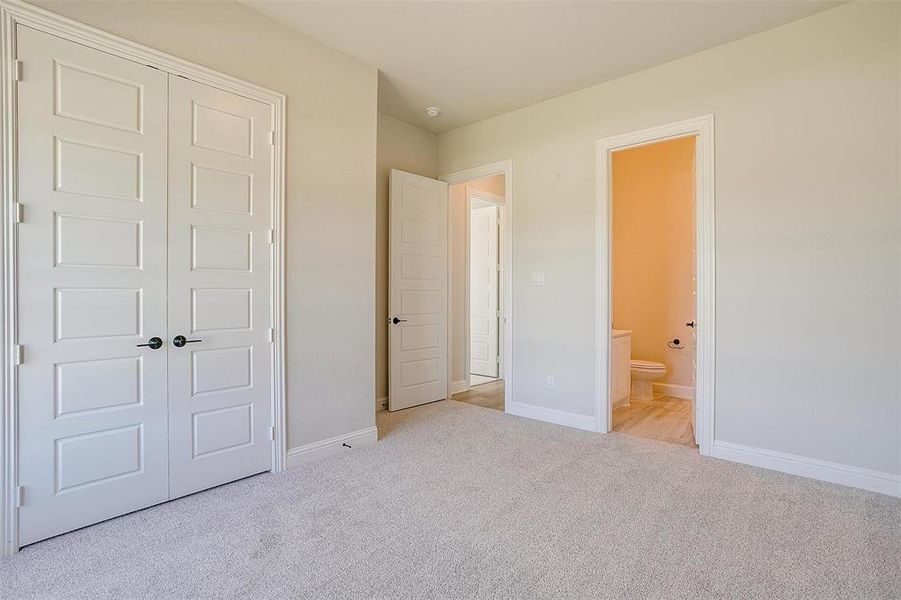 Unfurnished bedroom with light carpet, a closet, and connected bathroom