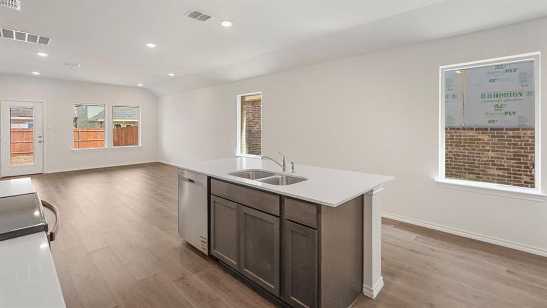 Kitchen island with white countertop, dual stainless steel sinks, and integrated dishwasher