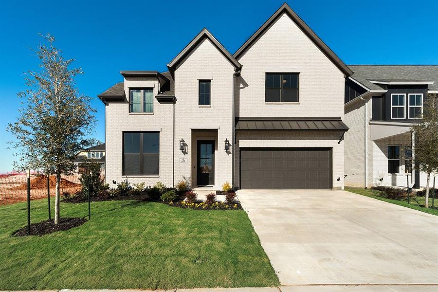 Modern farmhouse style home featuring concrete driveway, brick siding, a front yard, and an attached garage