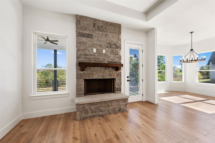 Unfurnished living room with a fireplace, light wood finished floors, a chandelier, and healthy amount of natural light
