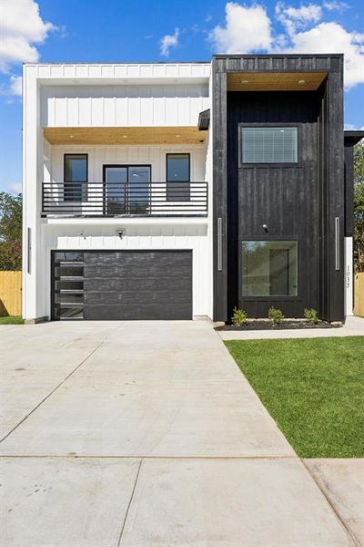 Contemporary house with a balcony, board and batten siding, concrete driveway, and a garage