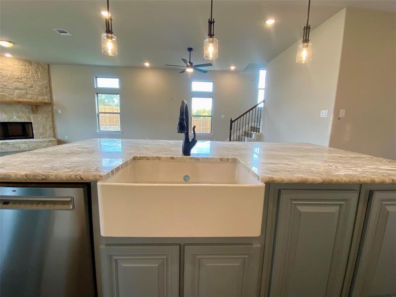 Oversized island with additional cabinets on both sides, extra counter space, and apron front farm sink.