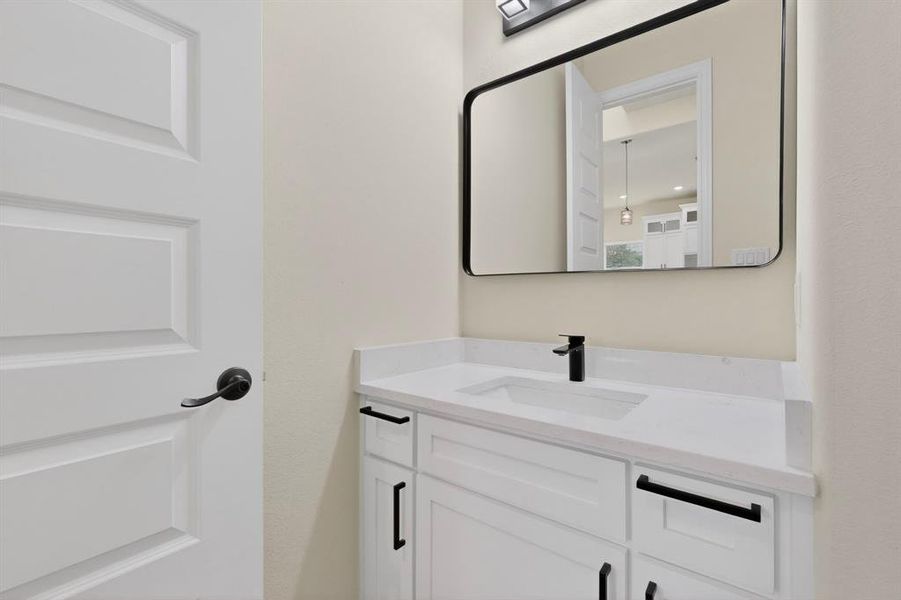 White shaker-style vanity with stone-finish countertop, undermount sink, and matte black faucet