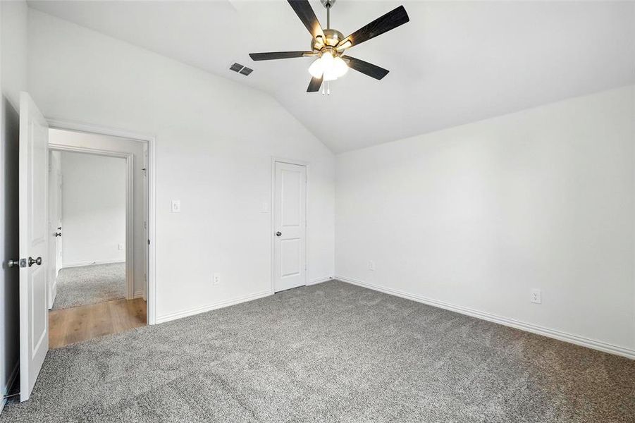 Unfurnished bedroom with carpet flooring, vaulted ceiling, and ceiling fan