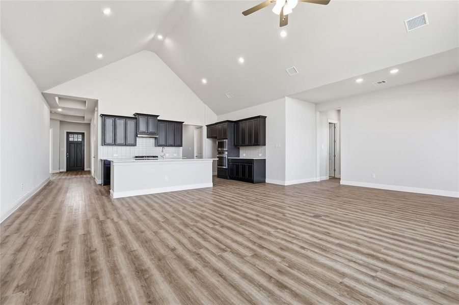 Unfurnished living room with a high ceiling, a ceiling fan, light wood finished floors, and recessed lighting Unfurnished living room with a high ceiling, a ceiling fan, light wood finished floors, and recessed lighting