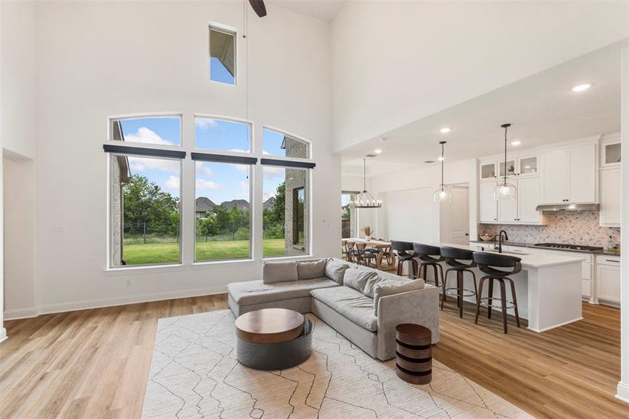 Living area with light wood-type flooring, a high ceiling, and recessed lighting Living area with light wood-type flooring, a high ceiling, and recessed lighting