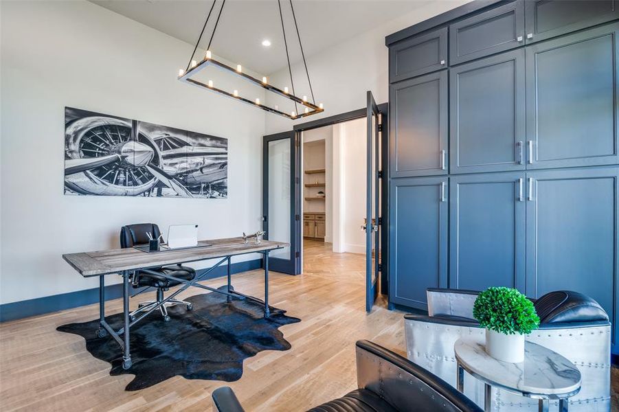 Home office with light hardwood / wood-style floors and a notable chandelier