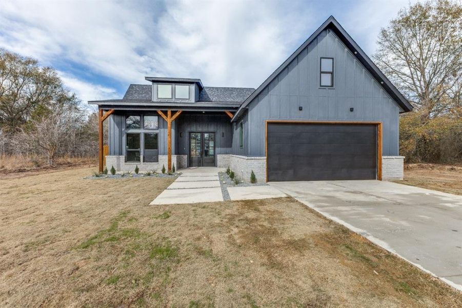 Modern farmhouse style home with a front lawn and a garage