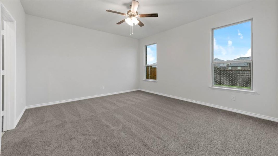 Unfurnished room featuring dark colored carpet and a ceiling fan Unfurnished room featuring dark colored carpet and a ceiling fan