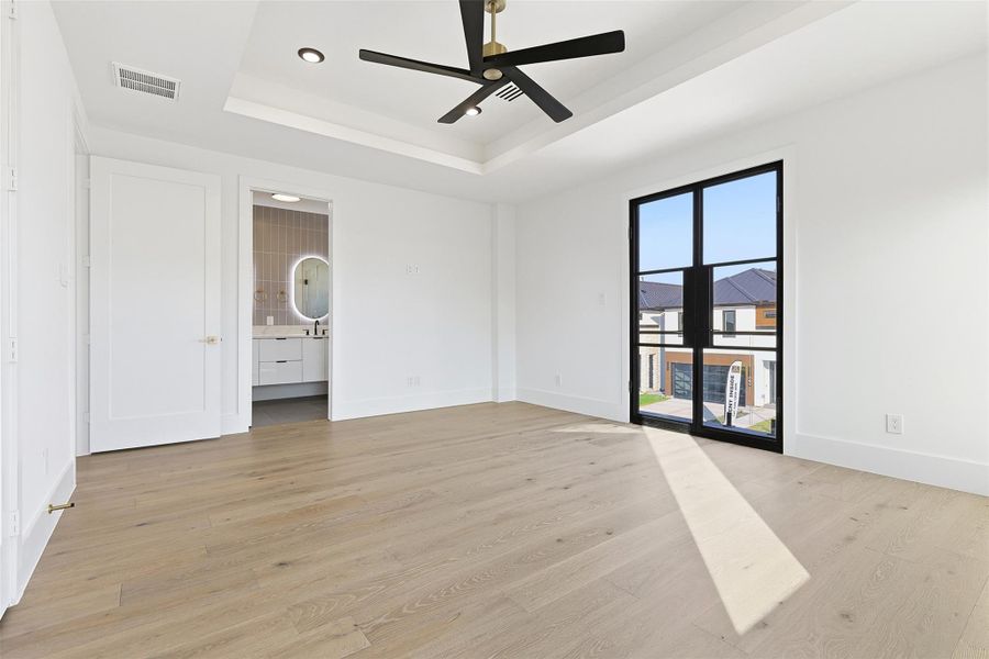 Same floorplan - different finishes. Natural light fills the room through floor-to-ceiling glass doors, highlighting the wide-plank light oak flooring found throughout the home.