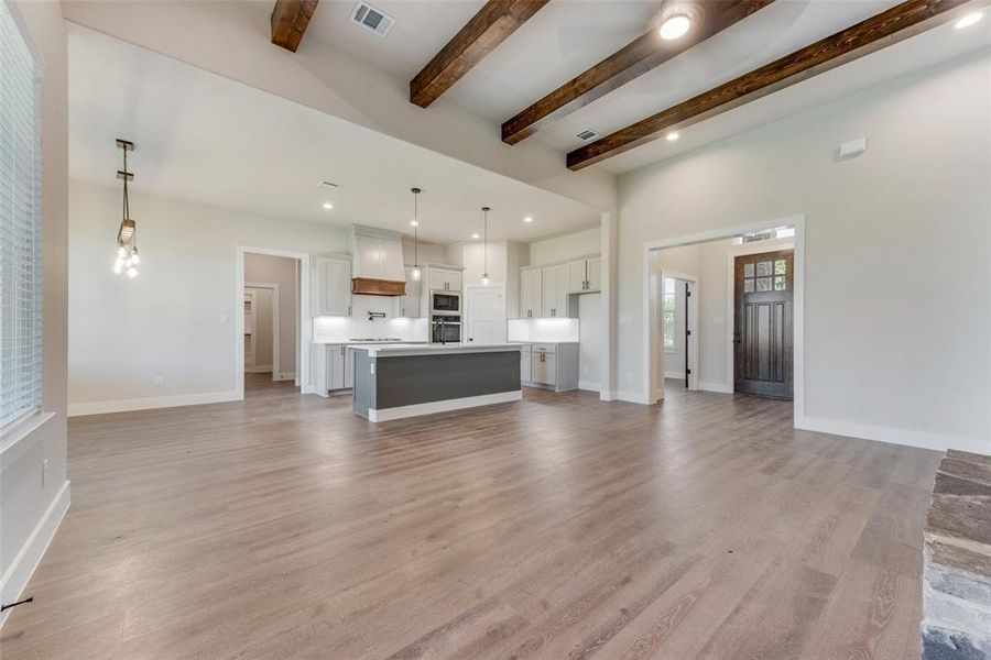 Unfurnished living room with beamed ceiling and light hardwood / wood-style flooring