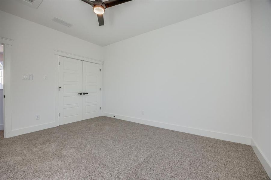 Unfurnished bedroom featuring carpet flooring, ceiling fan, and a closet