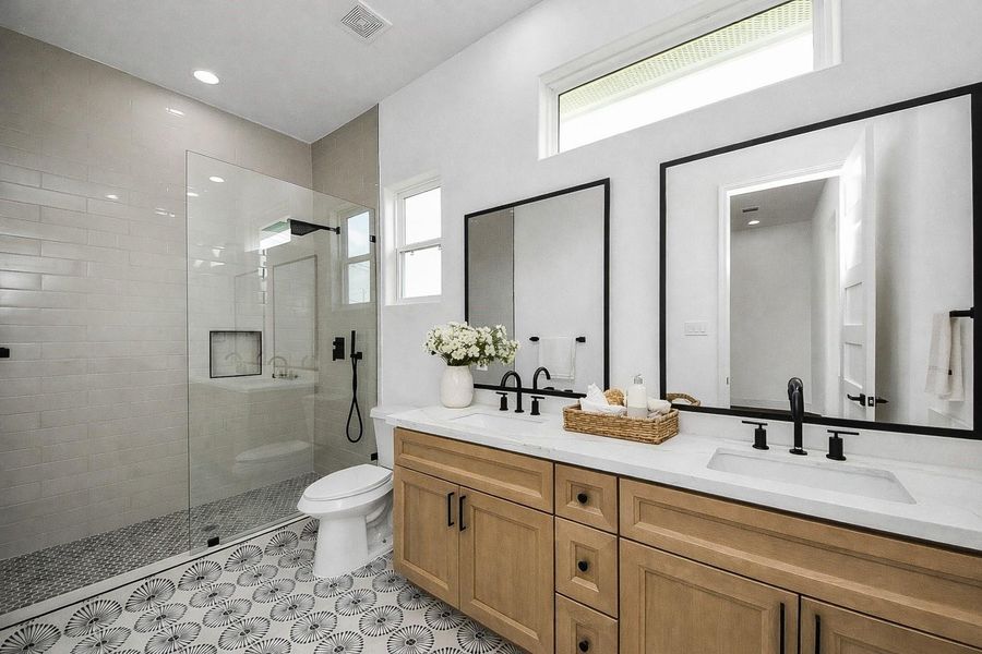 Modern guest bathroom featuring a large walk-in shower, dual vanity, and sleek finishes.