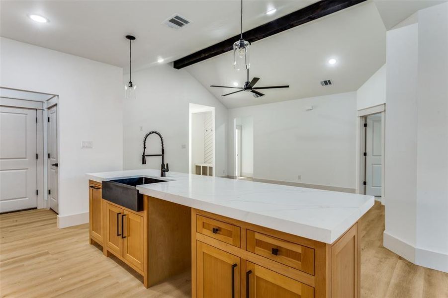 Kitchen with recessed lighting, light wood-style flooring, an island with sink, light stone counters, and a ceiling fan Kitchen with recessed lighting, light wood-style flooring, an island with sink, light stone counters, and a ceiling fan