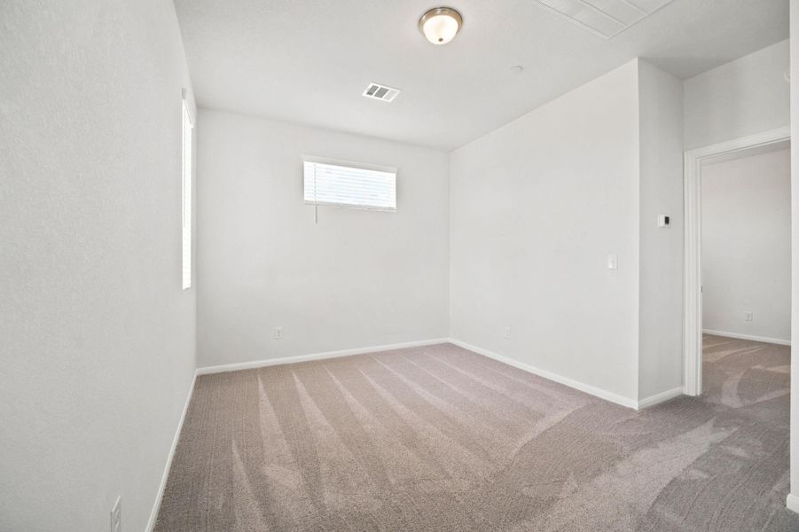 Soft carpeting pairs with neutral walls in this versatile secondary bedroom space.