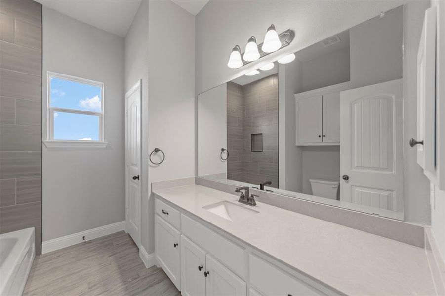 Full bathroom featuring vanity, hardwood / wood-style floors, shower with separate bathtub, and toilet