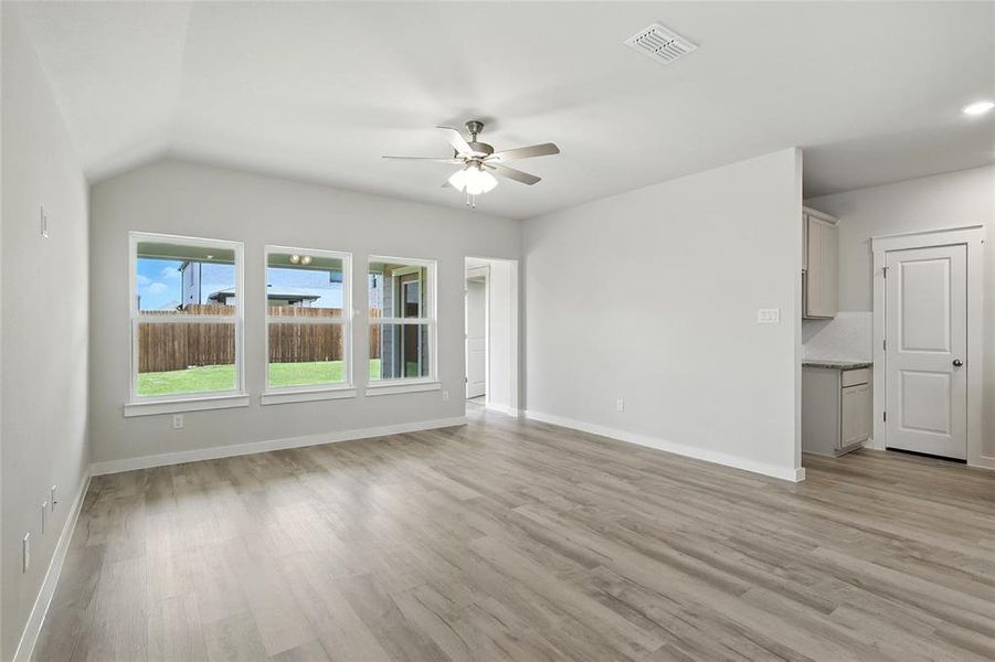 Unfurnished living room featuring a ceiling fan, light wood finished floors, and lofted ceiling