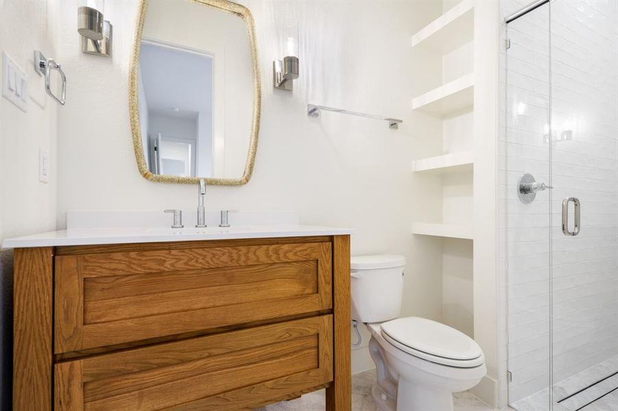 Bathroom featuring walk in shower, built in shelves, vanity, tile patterned flooring, and toilet