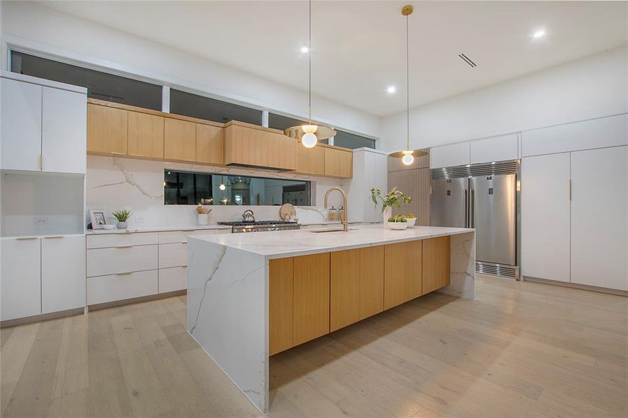 Kitchen featuring white cabinets, decorative light fixtures, an island with sink, and appliances with stainless steel finishes