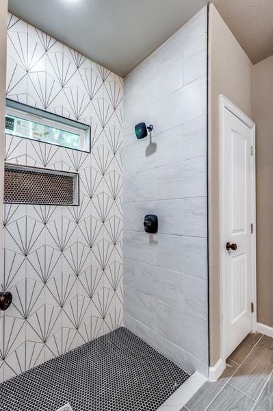 Bathroom with tiled shower and hardwood / wood-style flooring