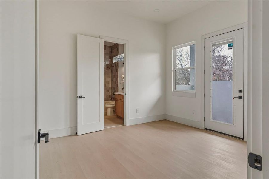 Unfurnished bedroom featuring access to outside, light wood-type flooring, and connected bathroom